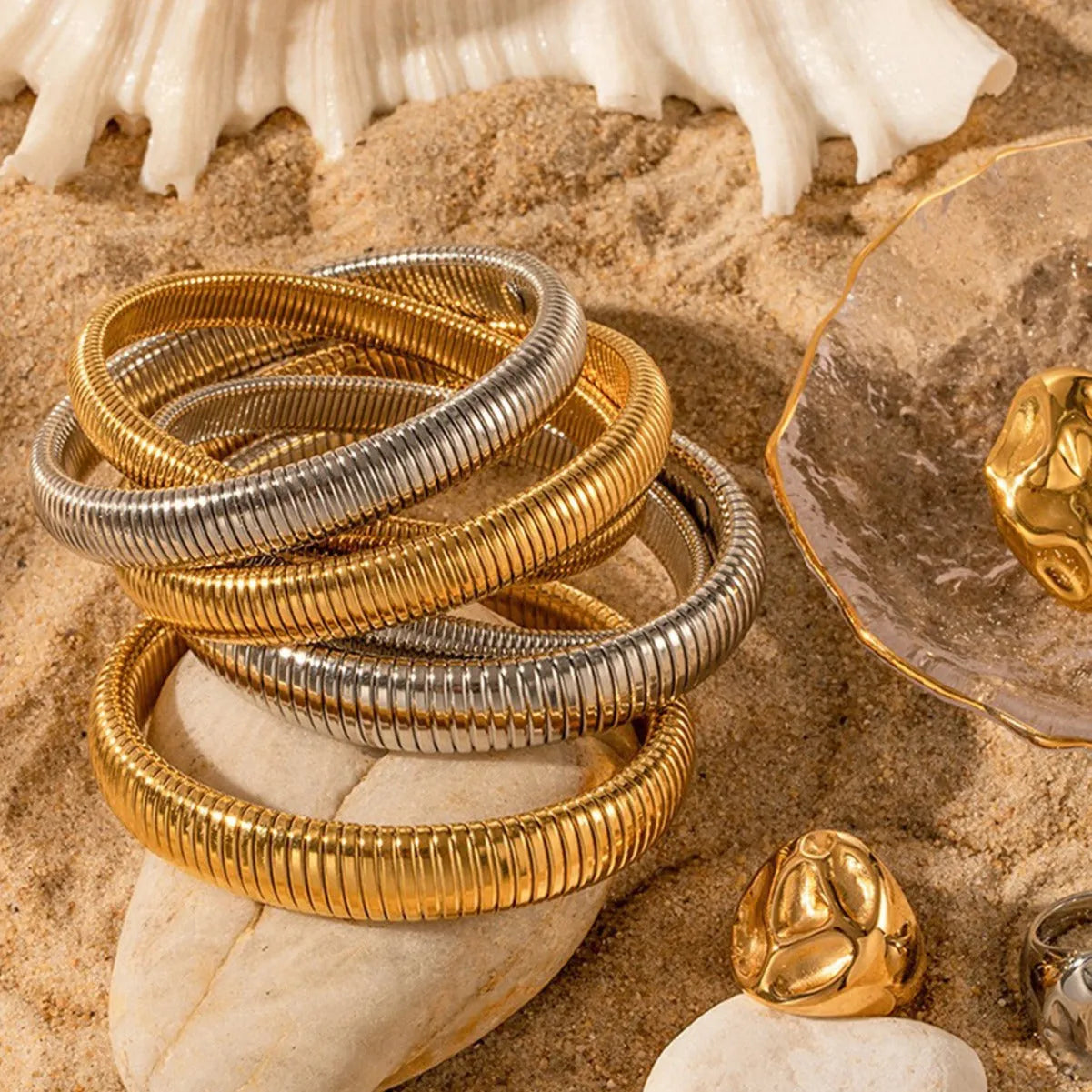 A gold women's elastic titanium steel bracelet with an exaggerated vertical stripe ring design, shown laid flat.