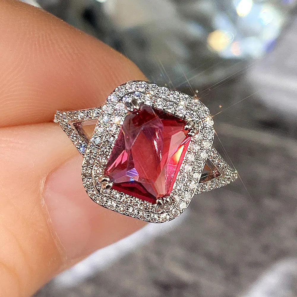 Red geometric square copper ring with clear princess-cut rhinestones, shown on a finger.