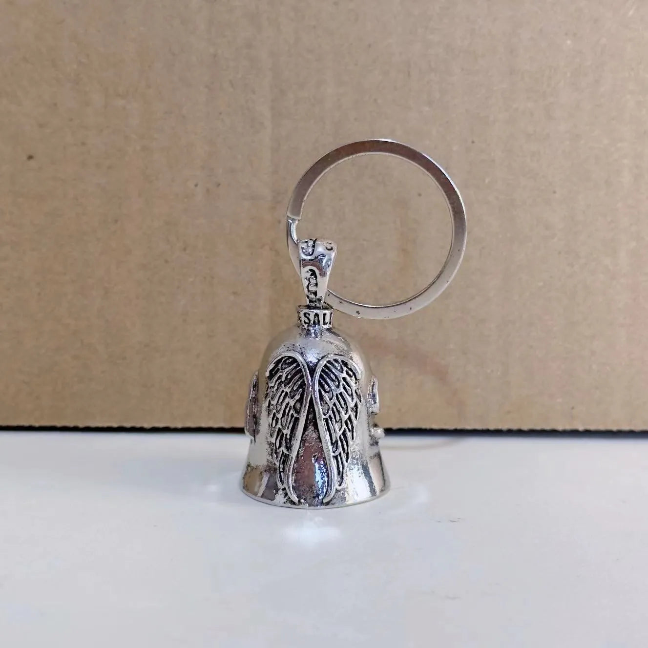 Vintage white angel feather wings alloy keychain and necklace set on a plain background.