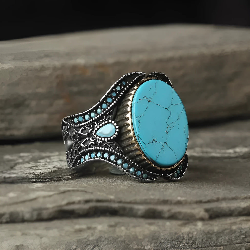 Men's antique silver alloy ring with a turquoise-coloured centre on a finger, showing its simple round design.