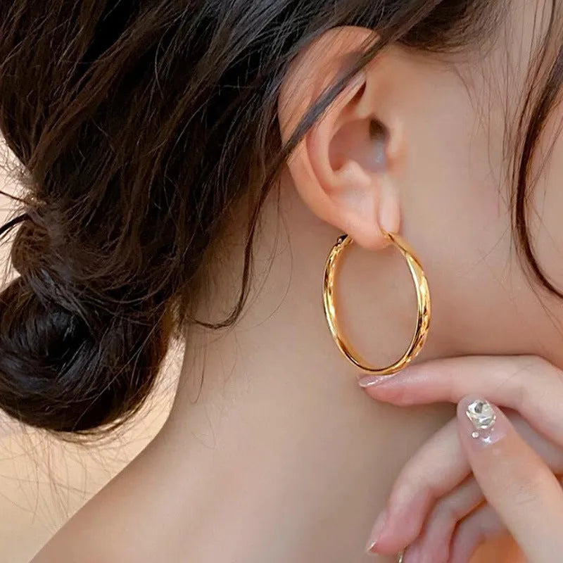 A pair of circular metal earrings with a gold electroplated finish, measuring 40mm.