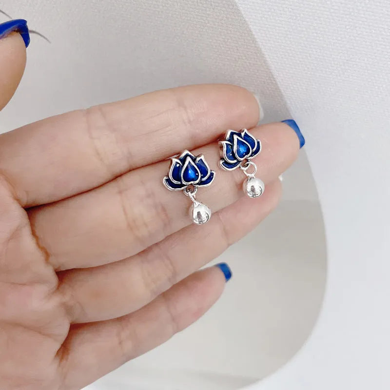 Close-up of blue lotus flower and seedpod tassel design on silver alloy ear studs