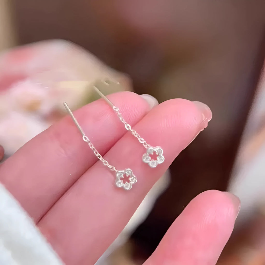 A pair of silver-coloured alloy drop earrings with a hollow floral petal design.