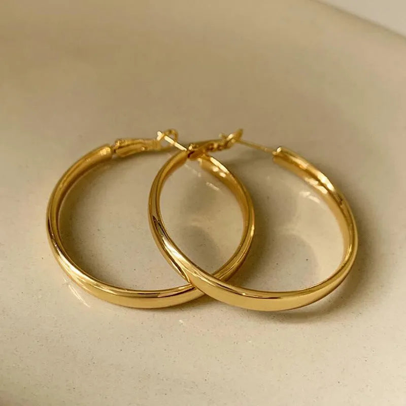 A pair of circular metal earrings with a gold electroplated finish, measuring 40mm.