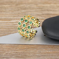 Gold coloured wide band ring with green zircon stones, shown from the side.