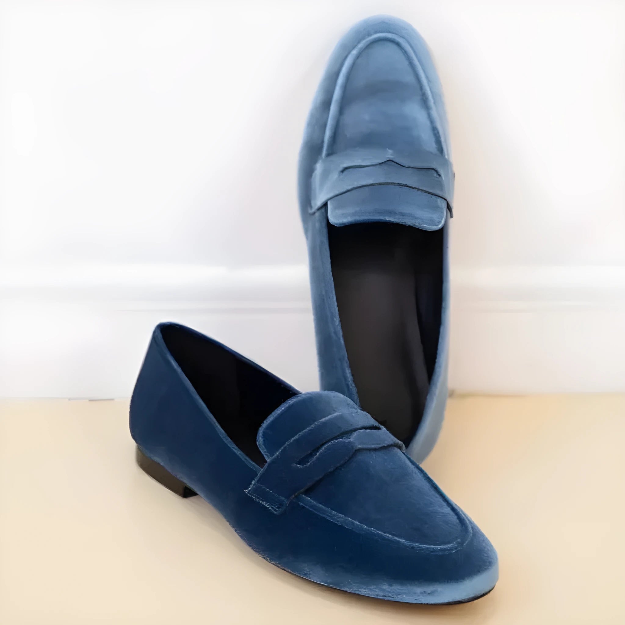 Blue women's flat loafers with black rubber sole showing round toe shape