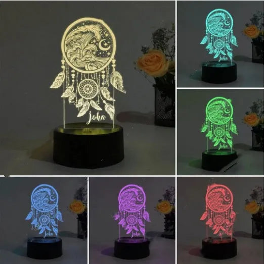Black-based acrylic dream catcher night light with remote control on a table next to USB cable.