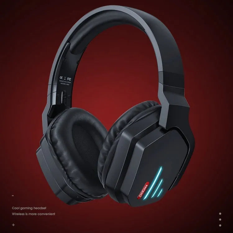 Luminous black wireless gaming headphones with head-mounted design on a desk with included 3.5mm cable and dust bag.