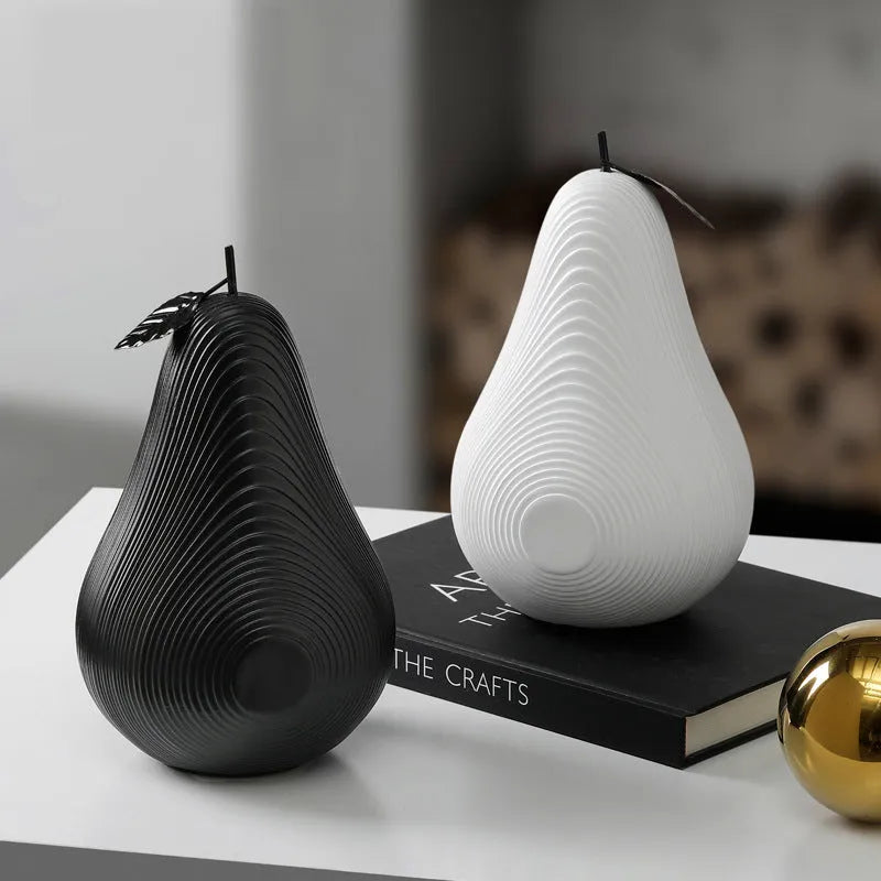 Decorative resin apple and pear crafts in white, orange, black, and blue on a shelf.