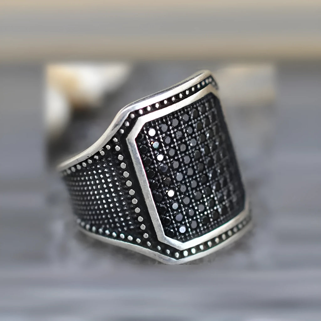 Black alloy ring with copper inlay detailing and a central zircon stone.