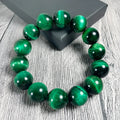 Polished green tiger eye stone bracelet with geometric beads on a wrist, showing size options.