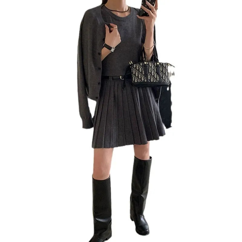 Women's black knitted two-piece set with long-sleeve cardigan, pleated vest skirt, 3D pattern, and a belt.