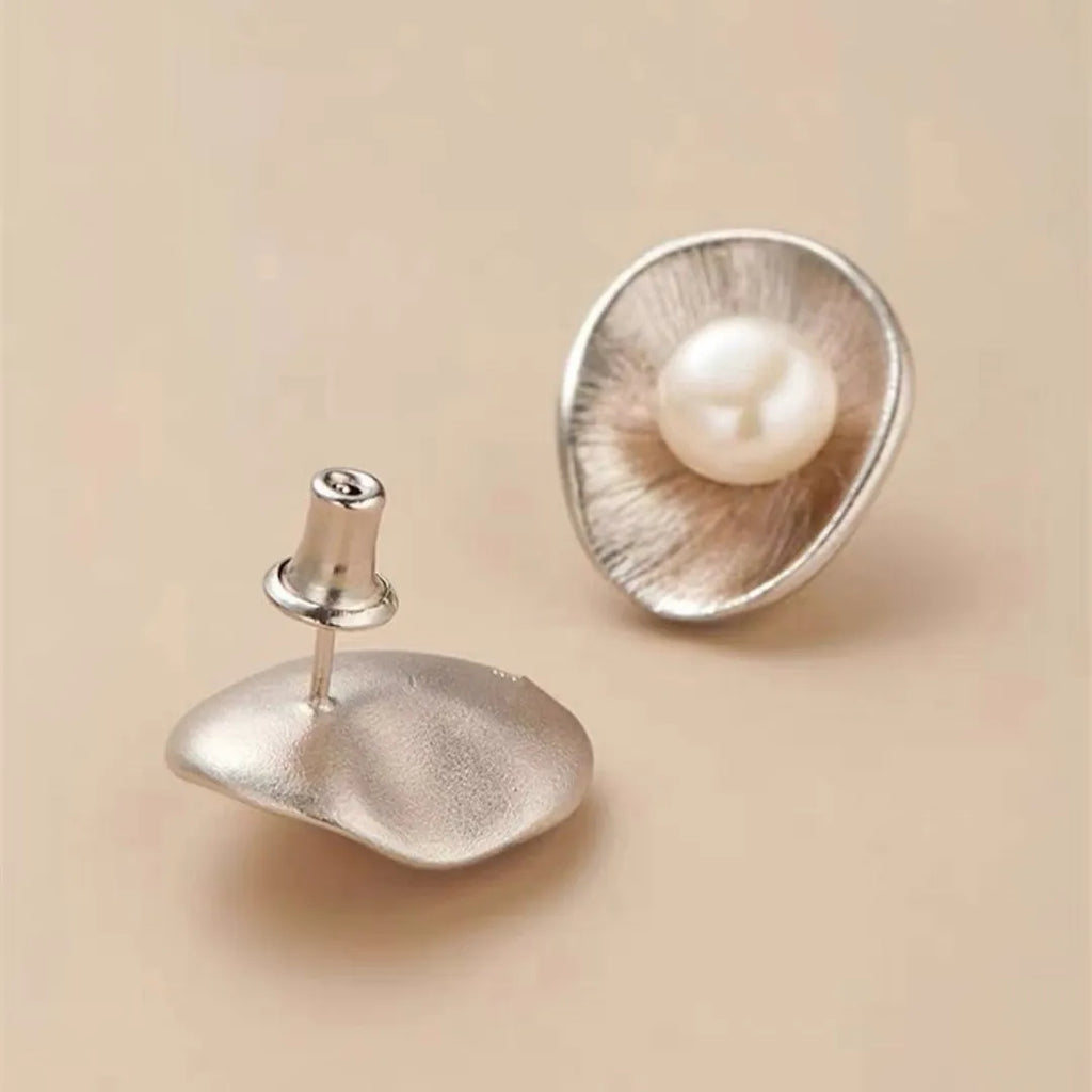 A pair of gold-coloured geometric sterling silver ear studs featuring a central pearl.
