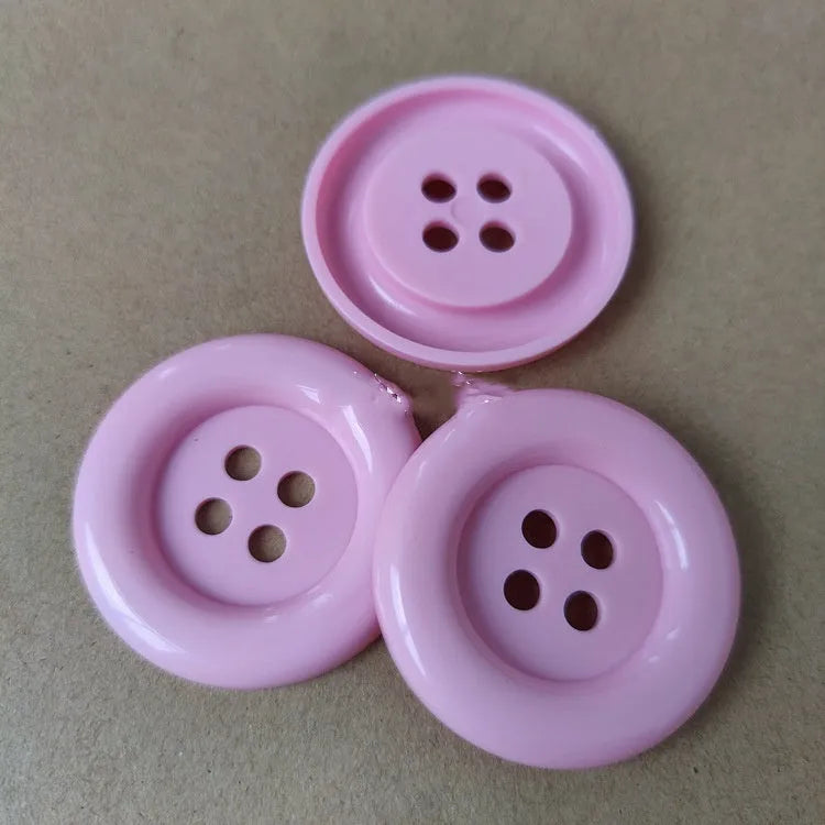 Large round plastic nylon buttons in multiple colours with four sewing holes for garment repair