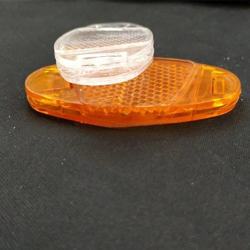 Yellow and white plastic bicycle spoke reflectors showing size of 7.2cm by 3.5cm.