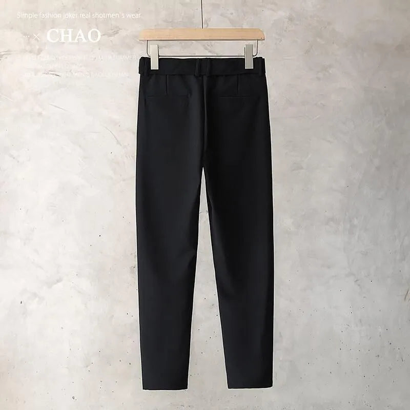 Boy wearing slim straight tapered wool trousers in a grey colour, showing the straight leg opening and belt loops.