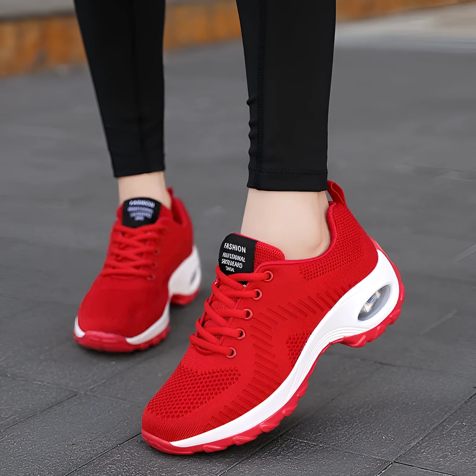 Red and black women's low-top mesh sneakers with front laces and a round toe, showing a mid-heel sole.