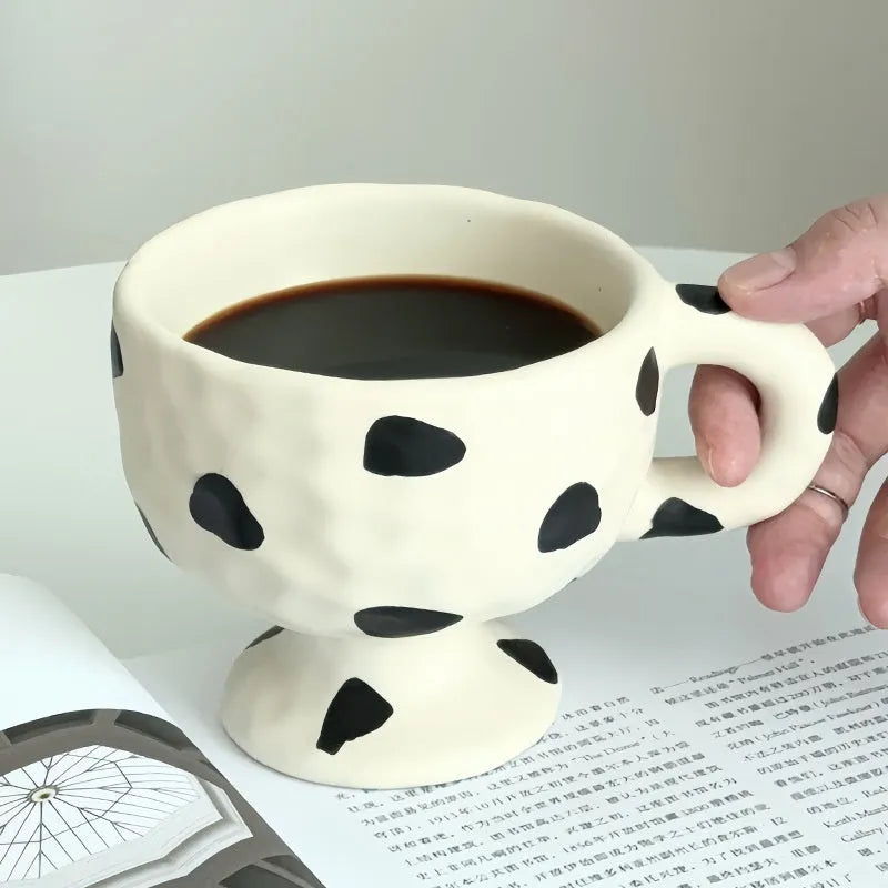 Hand-pinched irregular shaped ceramic mug in a solid colour on a table