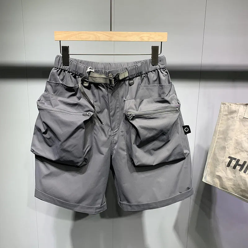 Men's loose-fit black work shorts with pockets, shown on a model, above the knee length.