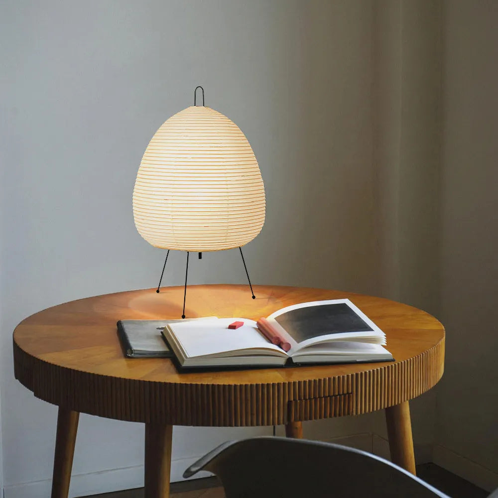 Japanese style rice paper table lamp with aluminium base on a wooden table.