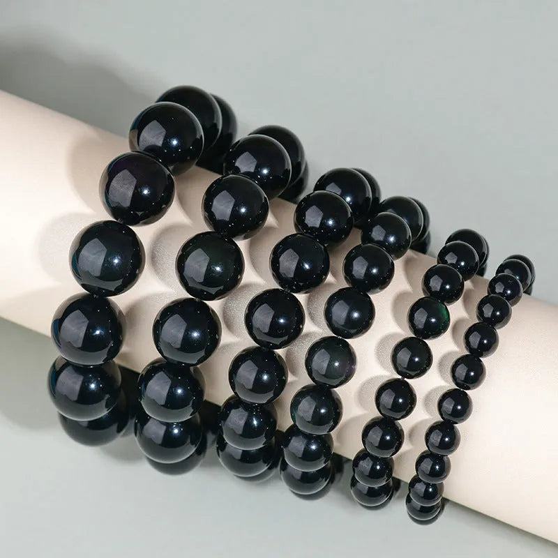 Hand-woven black obsidian bracelet with round beads, shown as a couple's set on a wrist.