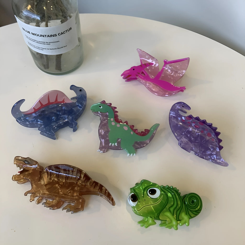 Dinosaur acrylic hair clip with jaw grip in various dinosaur designs including pink pterosaur and green stegosaurus