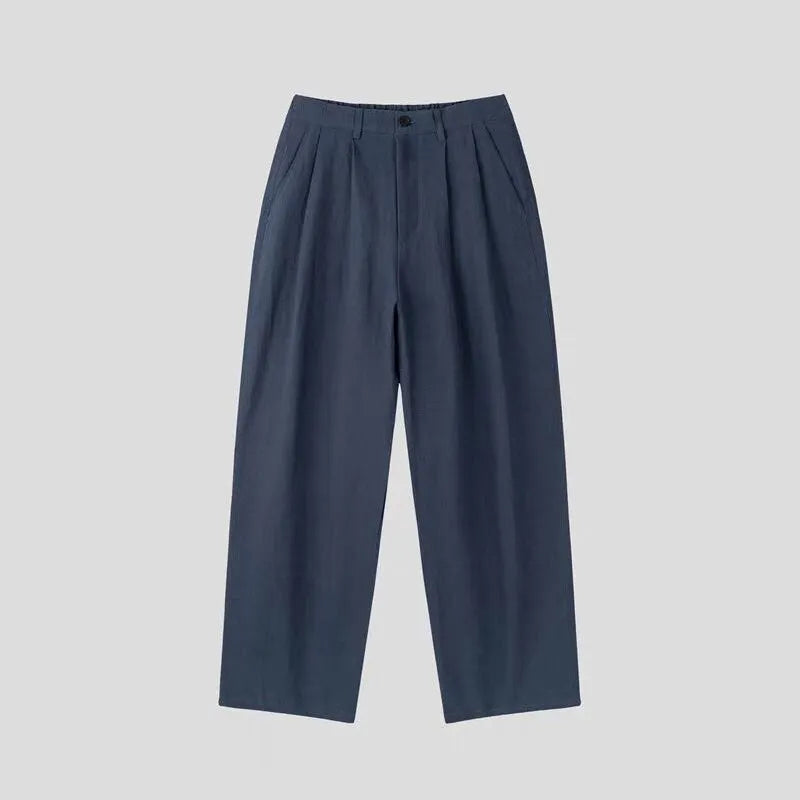 Man wearing apricot wide-leg cotton linen trousers with a mid waist and zip fly.