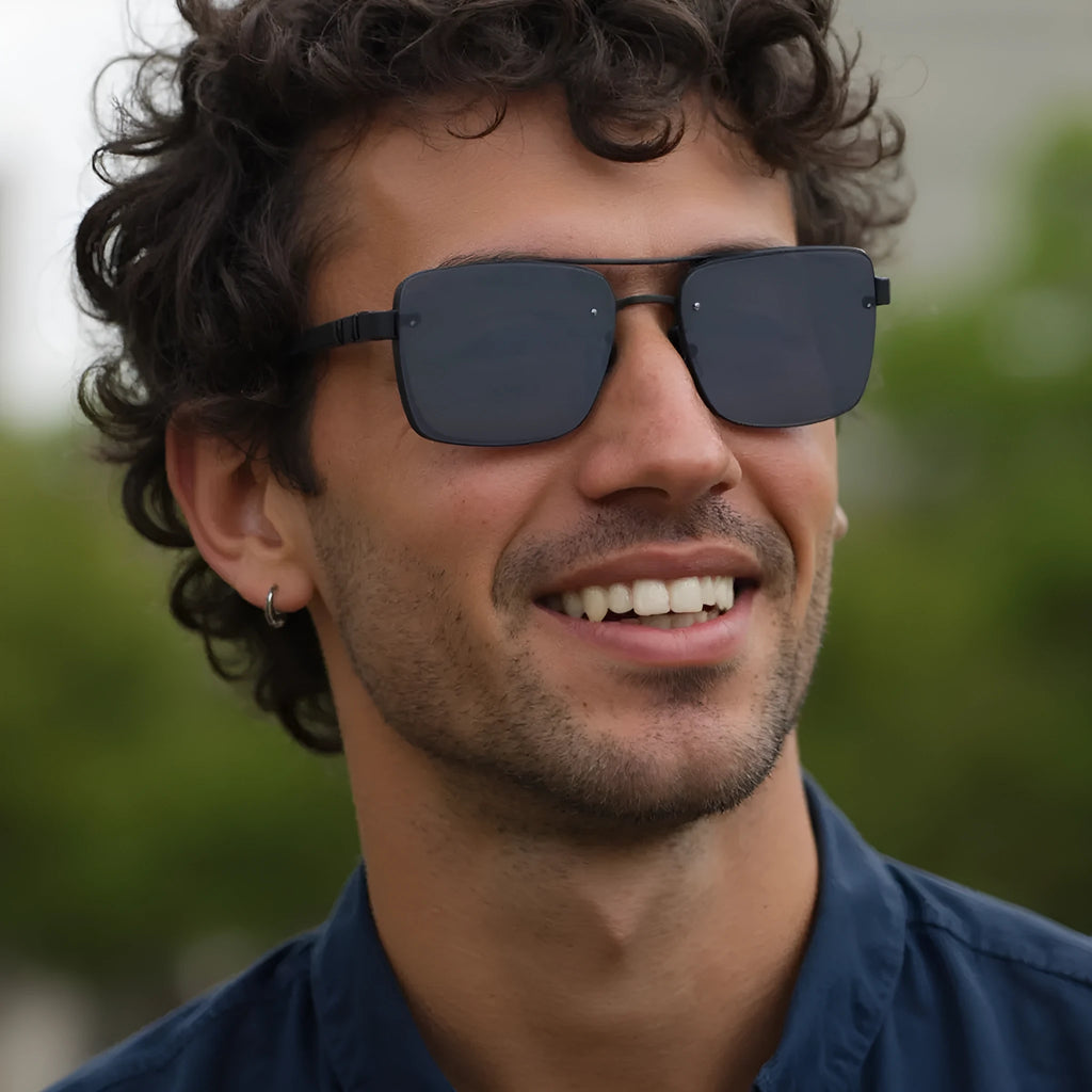 Men's vintage sunglasses with gold frame and grey lenses on a plain background.