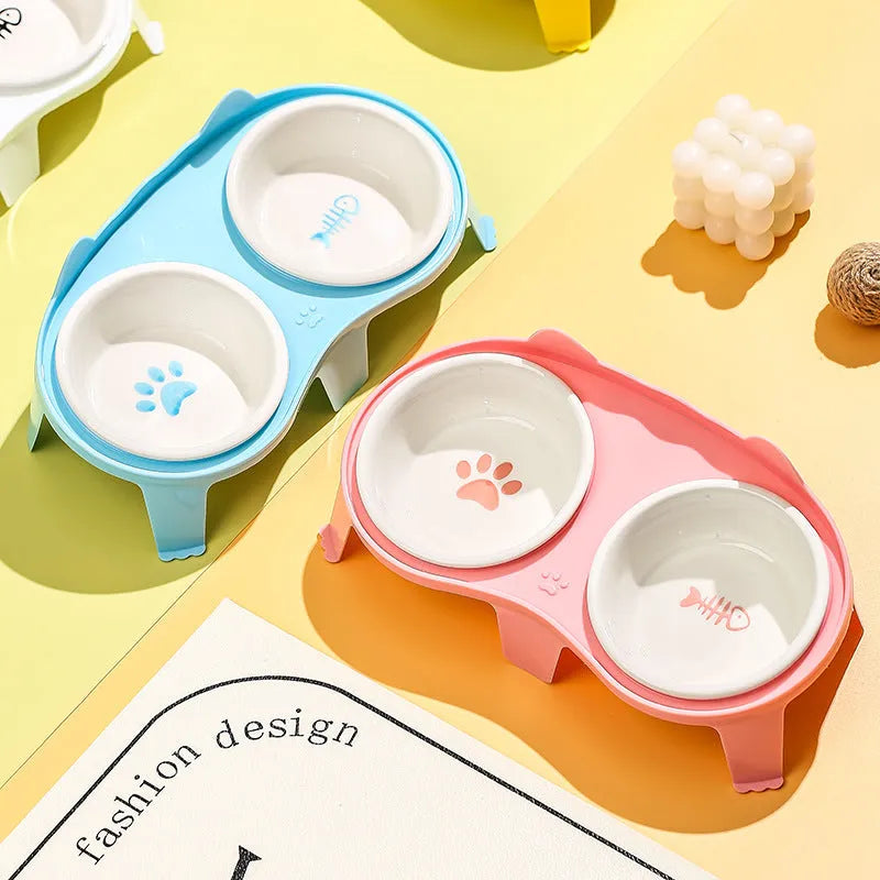 Blue ceramic cat food and water bowls sitting in a white elevated tilted stand with a hook