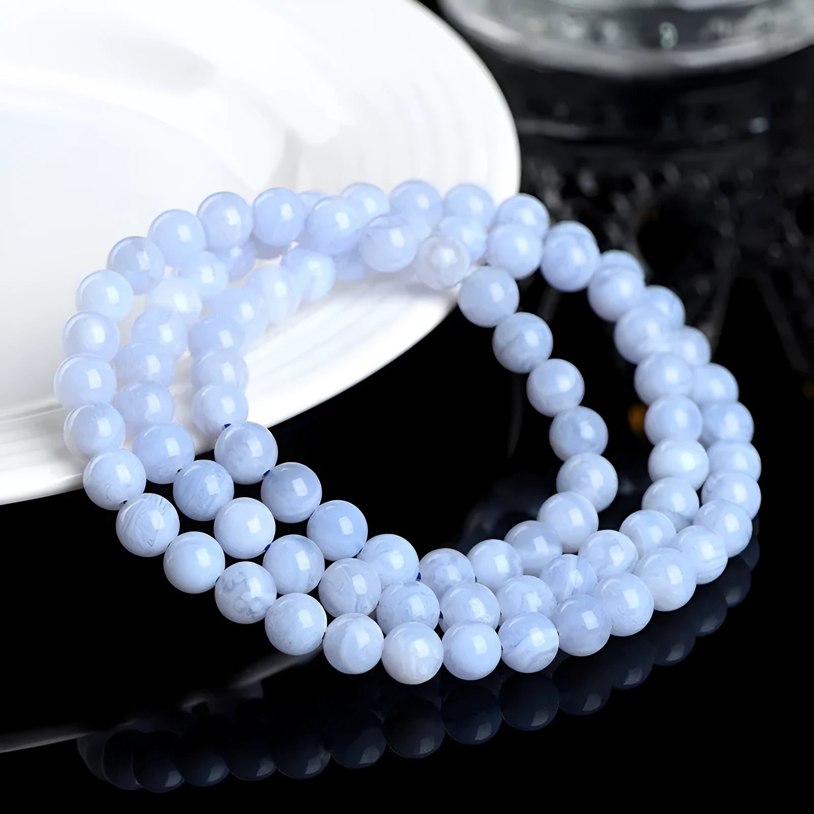 Blue striped agate bead bracelet with Ruyi charm on a wrist.
