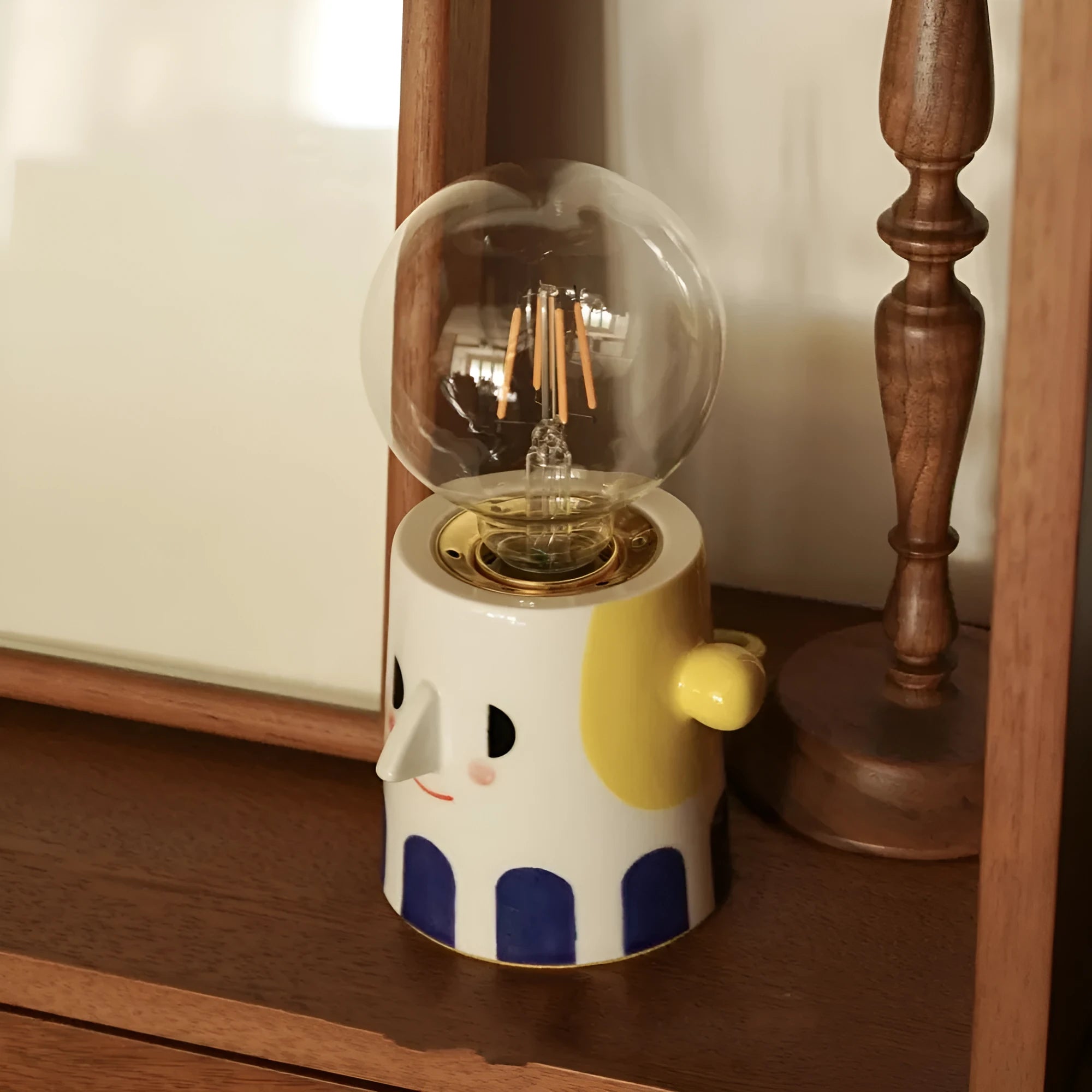 Handmade ceramic bedside lamp with ball headlight design on wooden surface