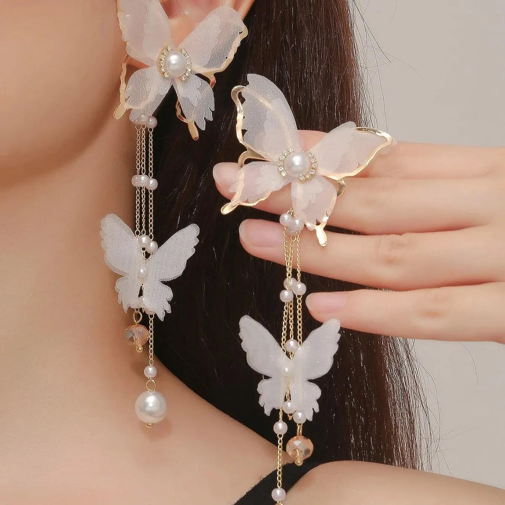 White butterfly-shaped earrings with lace patterns, pearl rhinestones, and a dangling tassel on a copper alloy base.