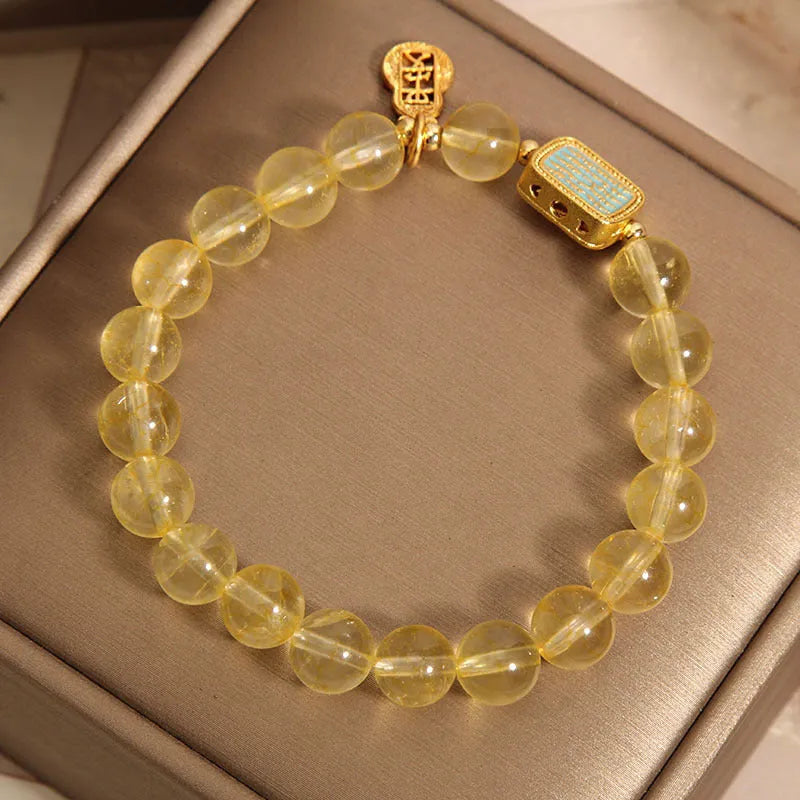 Women's yellow citrine crystal bracelet with sparkling rhinestone details on a white background.