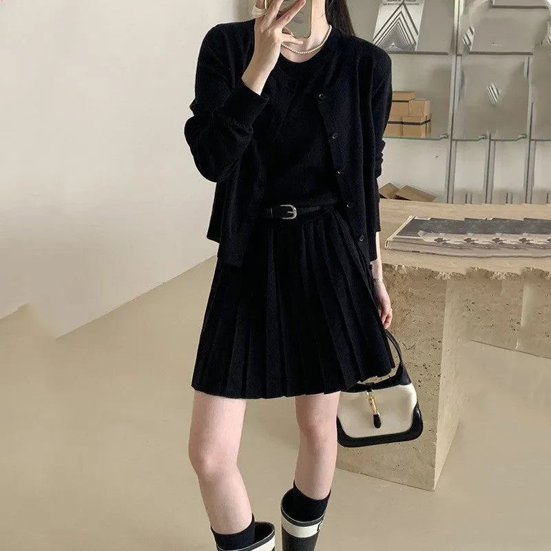 Women's black knitted two-piece set with long-sleeve cardigan, pleated vest skirt, 3D pattern, and a belt.