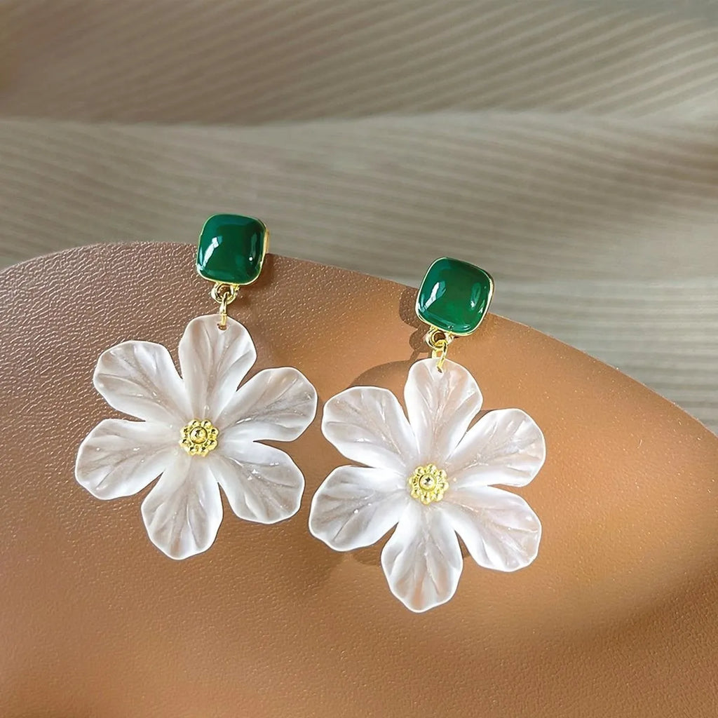 A pair of dark green alloy drop earrings with a floral design and clip-on fittings.