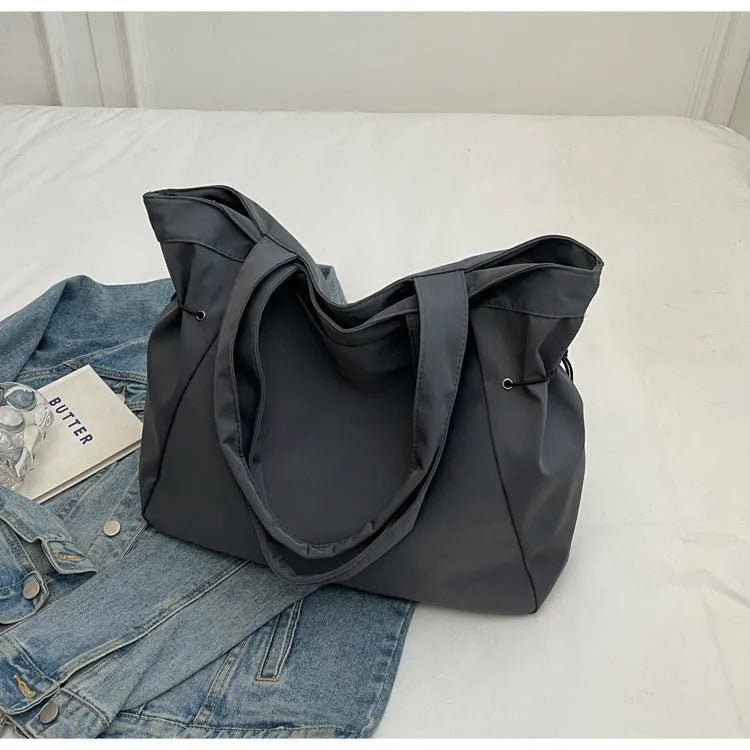 A soft folding Oxford cloth tote bag in a choice of five colours: black, light grey, dark grey, brown, and purple.