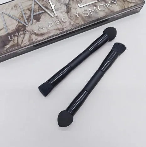 Double-headed concealer brush with tapered bristles and a miter sponge on a long black wooden handle.