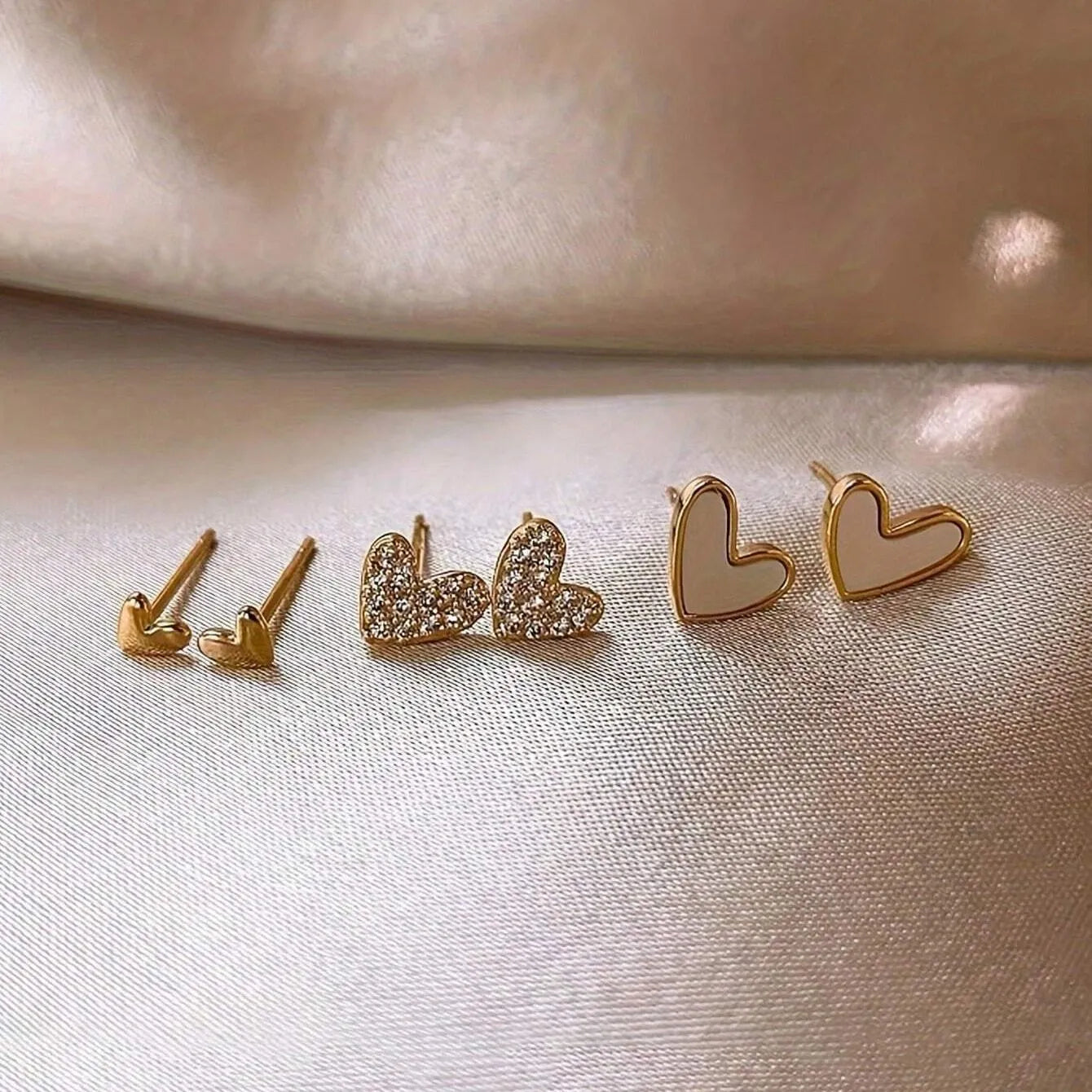 Three pairs of heart-shaped alloy earrings with electroplated finishes in gold, black, black-white, and pink colours
