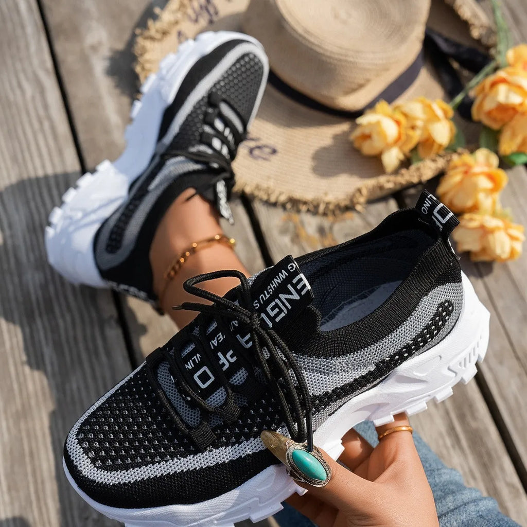 Women's Flyknit mesh lace-up sneakers in a grey colourway, showing the breathable upper and rubber sole.