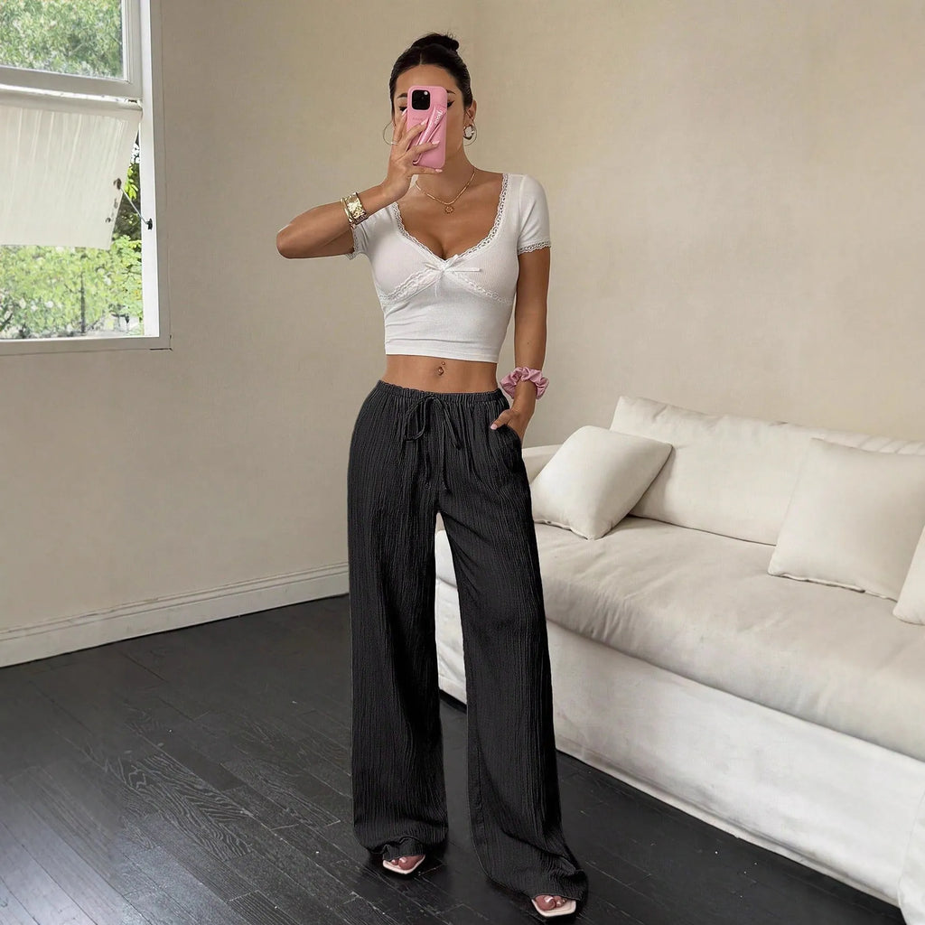 Women's black wide-leg trousers with lace-up waist detail and flowy silhouette