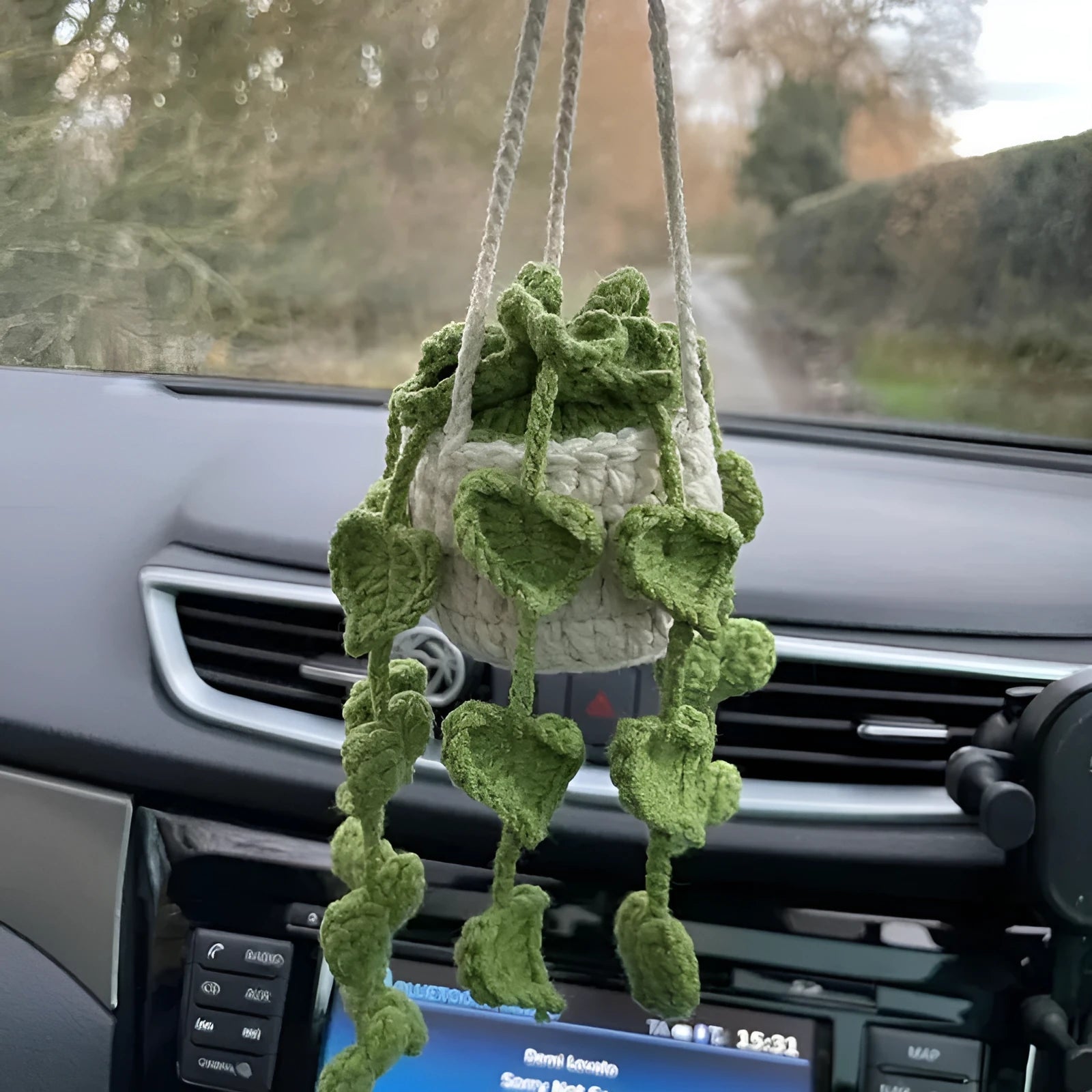 Green and white knitted wool car plant ornament with basin base and hanging rope.