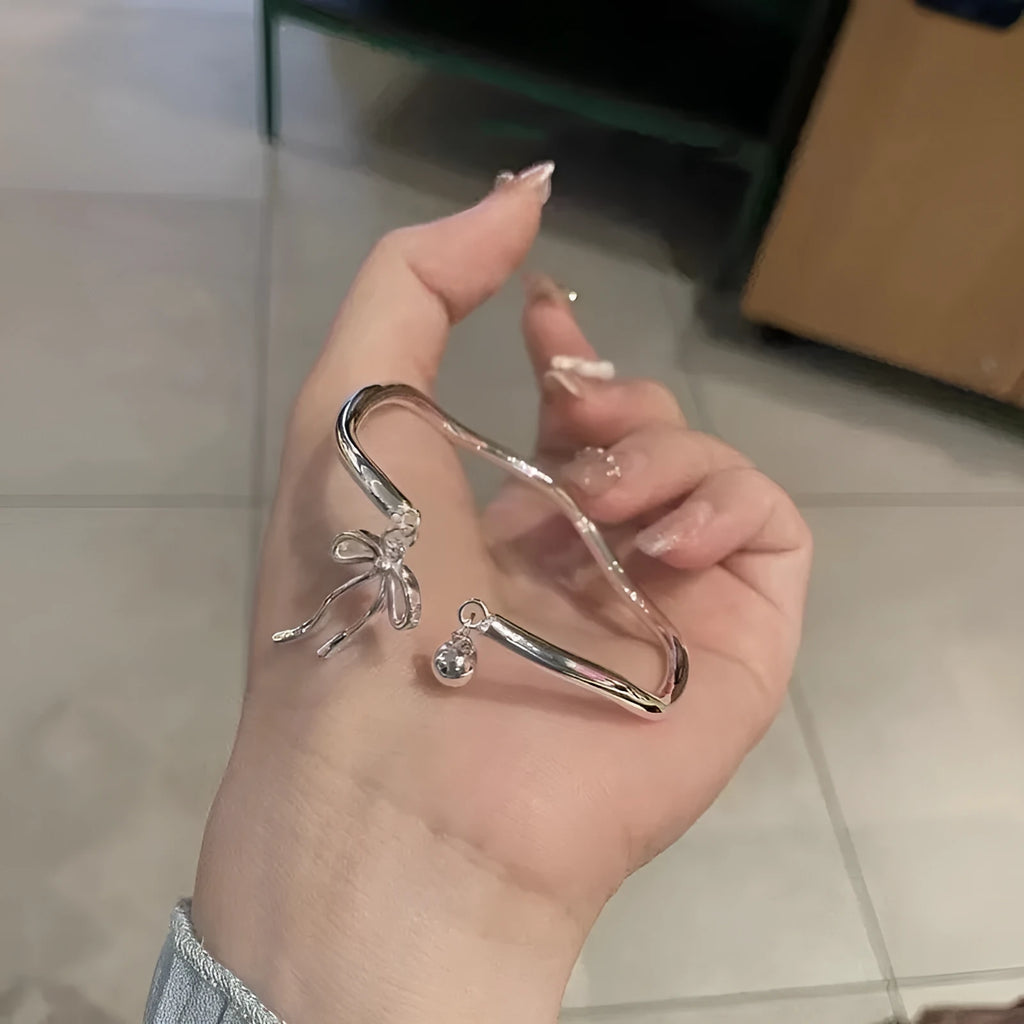 Silver bow adjustable bracelet with bell opening clasp on wrist