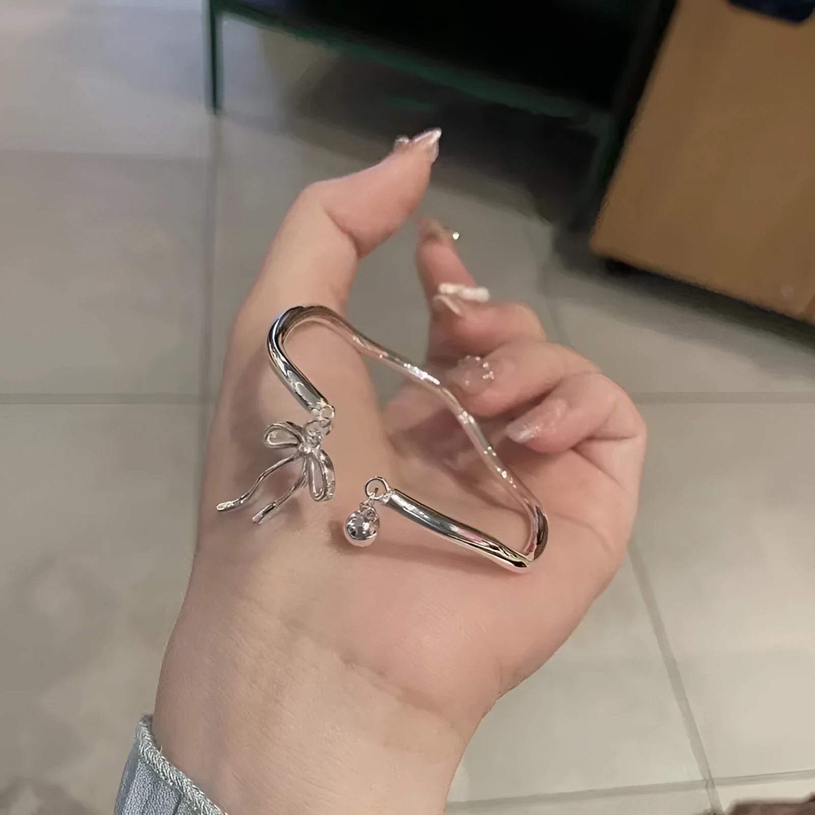 Silver bow adjustable bracelet with bell opening clasp on wrist