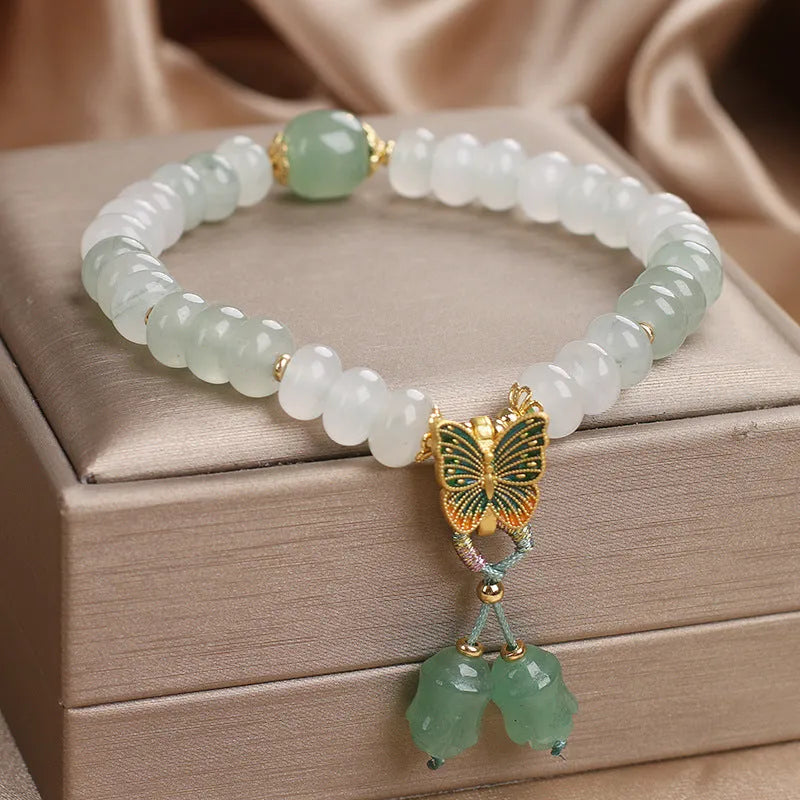 Green crystal abacus bead bracelet with butterfly charm and tassel detail, 17 cm length