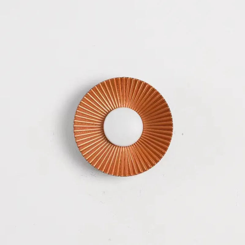 Round white and gold aluminium wall lamp mounted on a wall, LED light source visible.