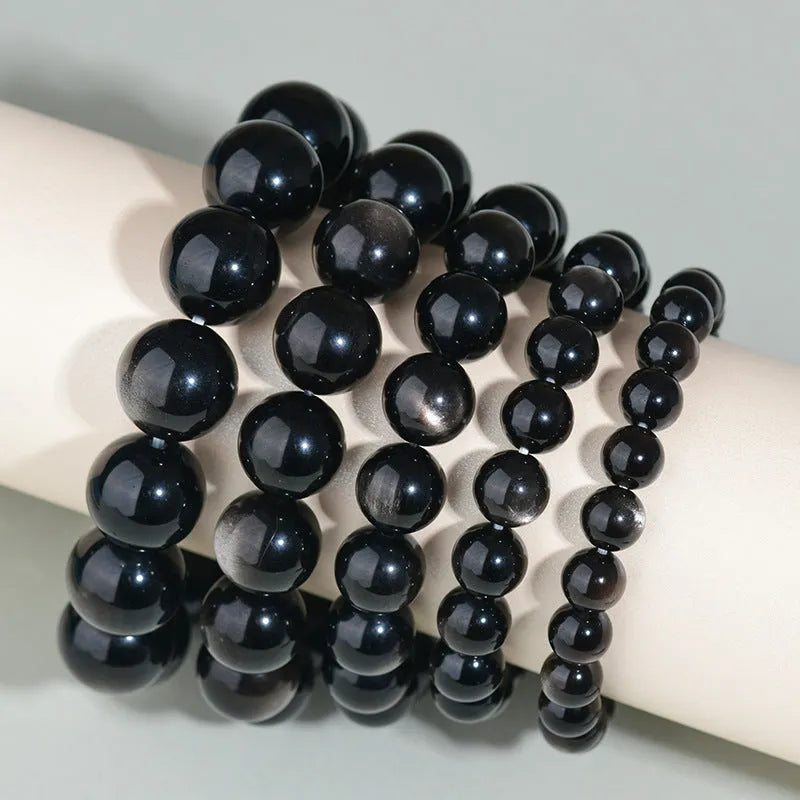 Hand-woven black obsidian bracelet with round beads, shown as a couple's set on a wrist.