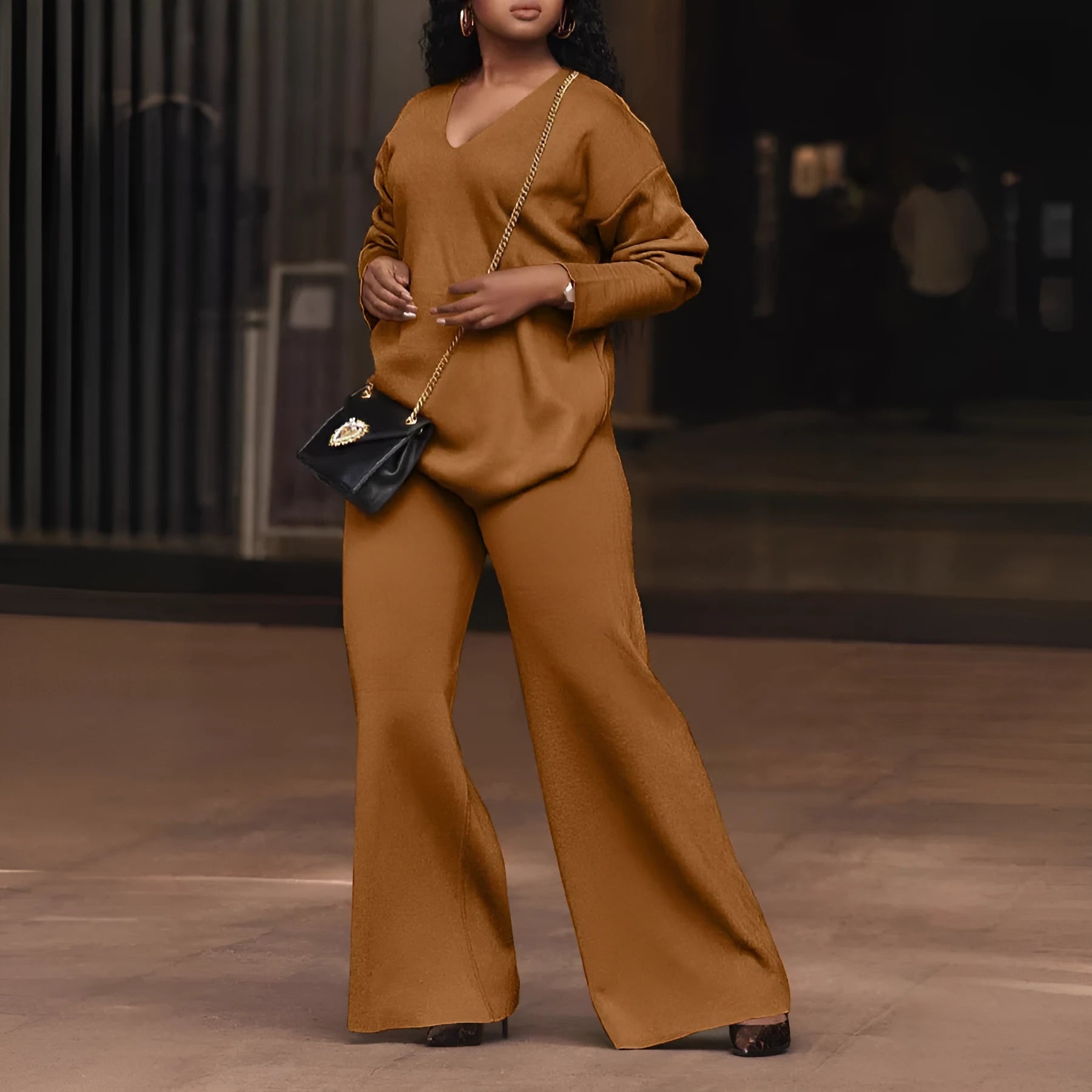Women's brown suede two-piece suit with split sleeve top and full-length trousers on a model.