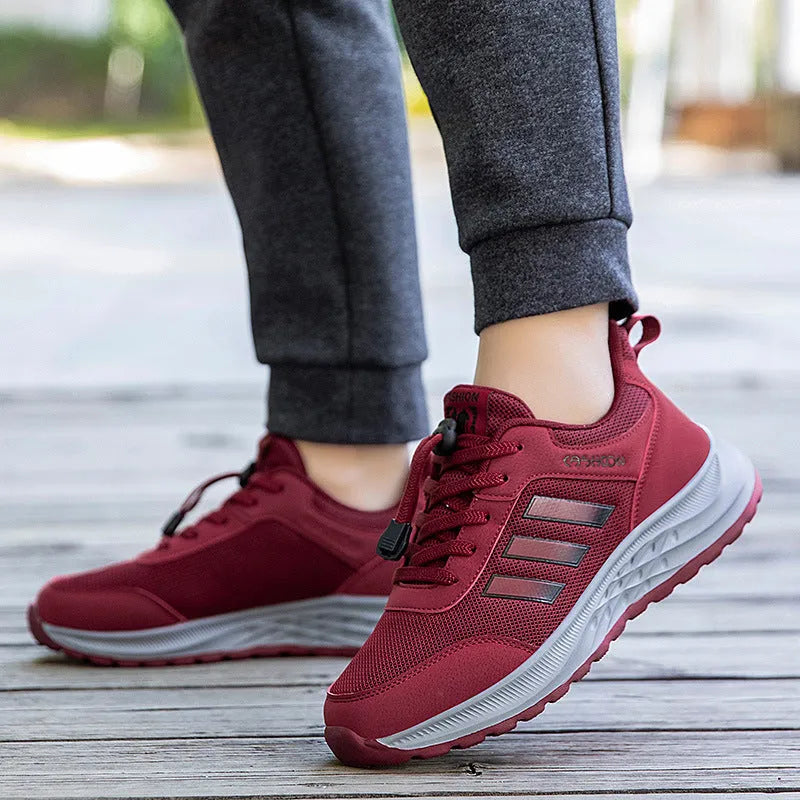 Men's and women's casual slip-on sneakers with mesh upper and elastic band in black, dark grey, purple, and purplish red.