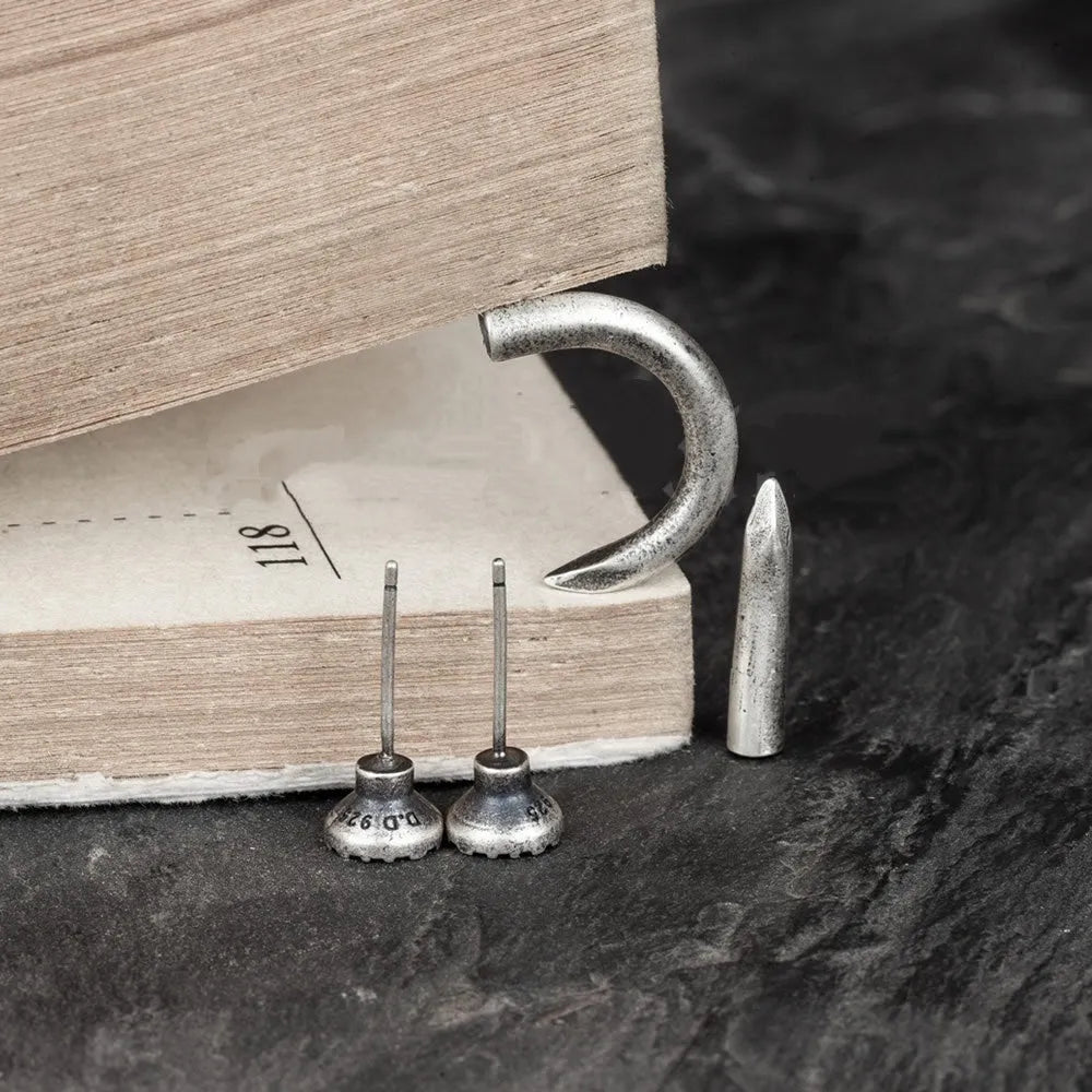 Close-up of a sterling silver punk stud earring with a retro nail design on an ear.