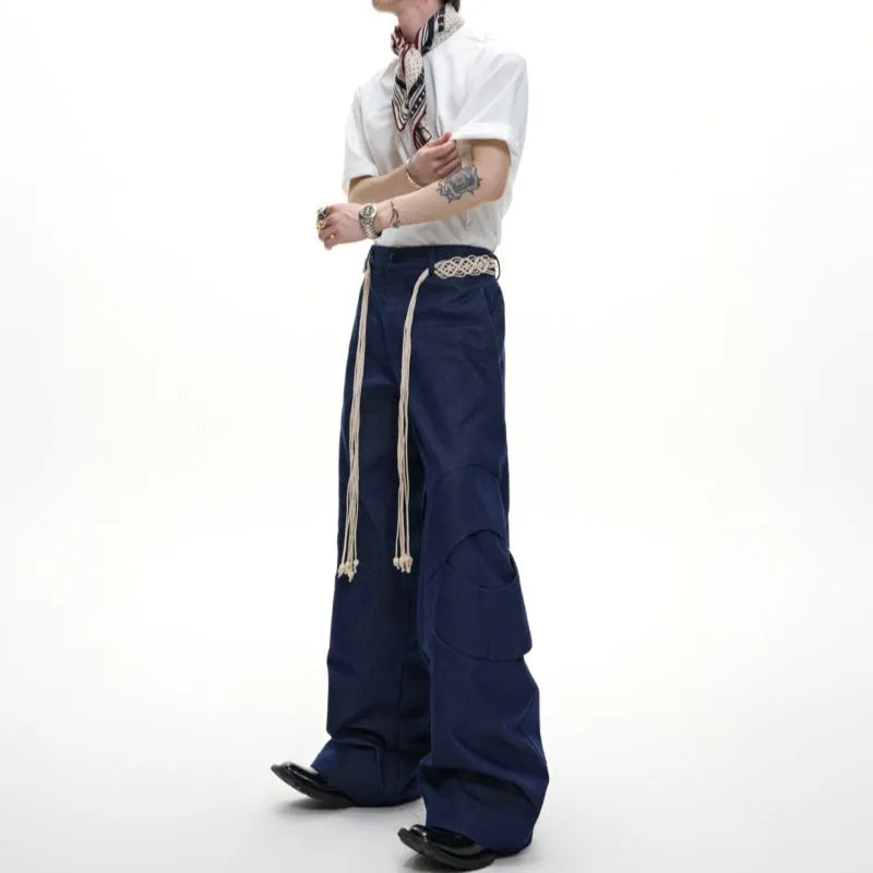 Men's dark blue cotton straight-leg jeans with loose fit, showing heavy 3D cutting, belt stitching, and decorative zip details.